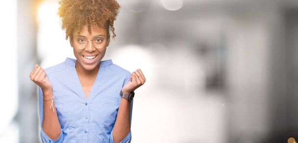 Mooie jonge Afro-Amerikaanse zakenvrouw over geïsoleerde achtergrond vieren verrast en verbaasd voor succes met armen verhoogd en open ogen. Winnaar concept. - Foto, afbeelding