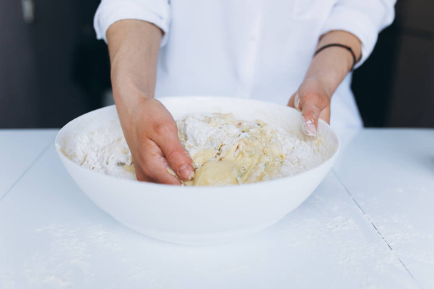 Female Hands Knead the Dough on a White Table - Foto, afbeelding