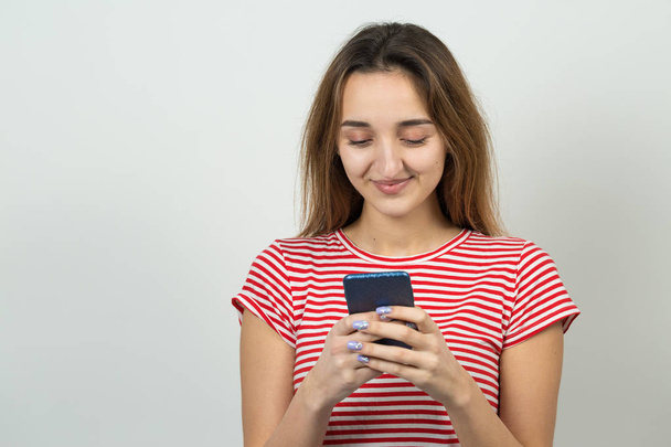 Young caucasian girl watching on smartphone on white background - Photo, Image