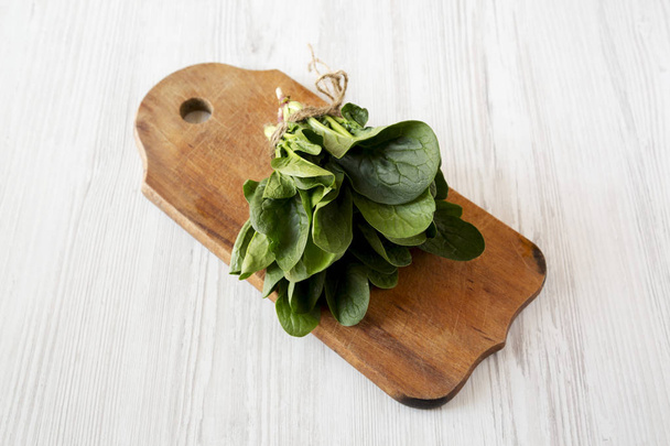 Fresh raw spinach on rustic wooden board on a white wooden backg - Fotó, kép