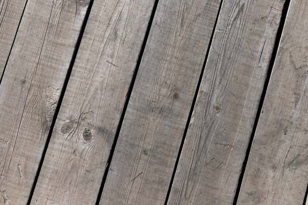 Buiten houten vloeren vanaf de planken. Knopen, krassen en zwarte lijnen tussen de planken. Textuur voor achtergrond. - Foto, afbeelding