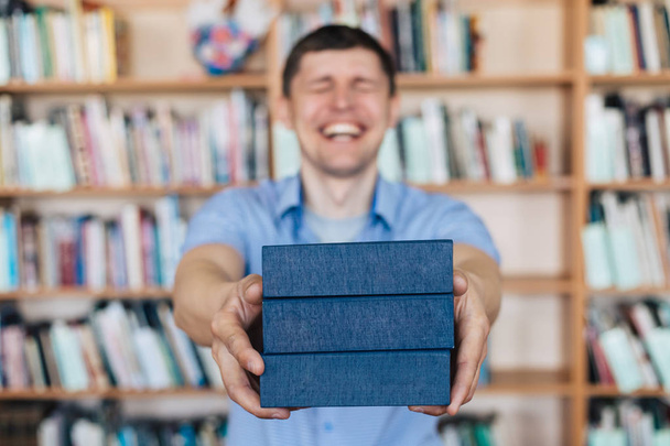 Mãos masculinas segurando uma pilha de livros. Homem segura uma pilha de livros
 - Foto, Imagem