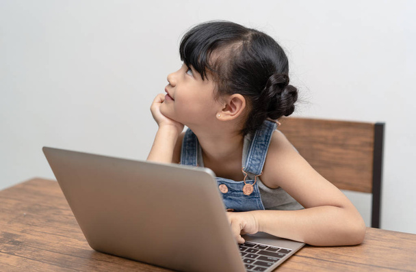 Pieni aasialainen tyttö innoissaan tietokoneoppiminen koulutyötä ja
 - Valokuva, kuva