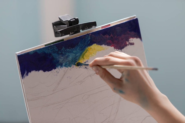 A lány művész festett egy képet vászonra olajfestékkel. Közelkép a festési folyamatról. - Fotó, kép