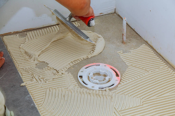 Tiler en reparatiewerk leggen tegel, troffel in een man hand - Foto, afbeelding