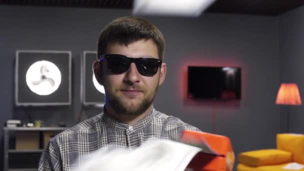 Aranyos ember vlogger beszél és tart műanyag fegyvert köpködés ki dollár bankjegyek - Felvétel, videó