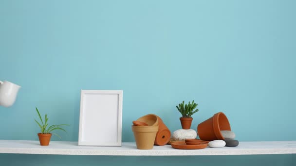 Moderni huoneen sisustus kuvakehys mallinnus. Valkoinen hylly vastaan pastelli turkoosi seinä keramiikka ja mehukas kasvi. Käsin kastelu ruukkuhämähäkki kasvi
. - Materiaali, video