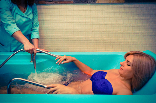 Mujer rubia relajándose en el salón de spa durante el masaje bajo el agua
 - Foto, Imagen