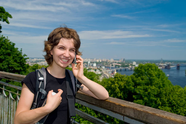 Young woman smiling and talking on the phone at beautiful backdrop of the city of Kyiv - Foto, Imagem