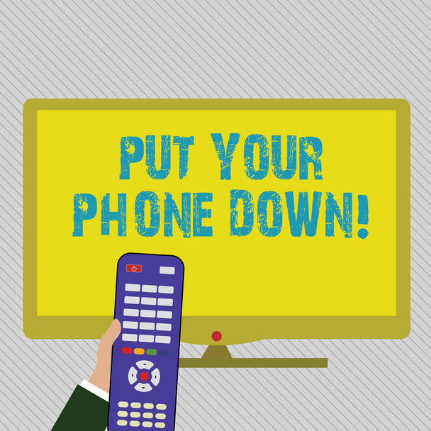 Text sign showing Put Your Phone Down. Conceptual photo end telephone connection saying goodbye caller Hand Holding Computer Remote Control infront of Blank Wide Color PC Screen. - Photo, Image