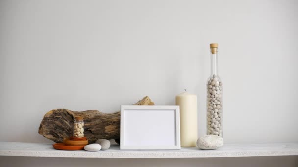 Modern szoba dekoráció képkeret mockup. Polc ellen fehér fal dekoratív gyertya, üveg és szikla. Kézi elhelyezés legyőz cserepes kaktusz növény. - Felvétel, videó