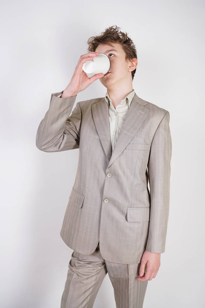 підліток чоловік у сірому діловому костюмі з папером Чашка кави в руці на білому фоні студії
 - Фото, зображення