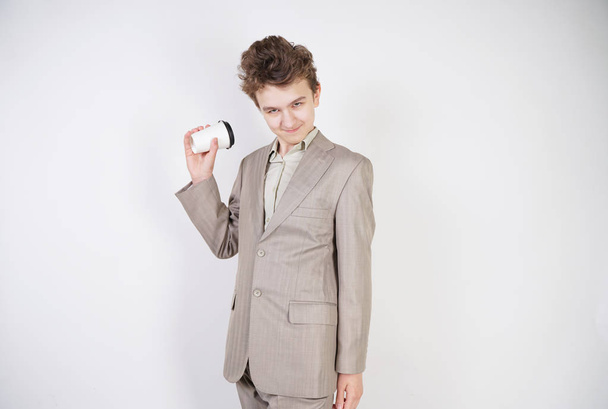 beyaz stüdyo arka plan üzerinde elinde kahve kağıt Fincan ile gri iş elbisesi genç erkek - Fotoğraf, Görsel