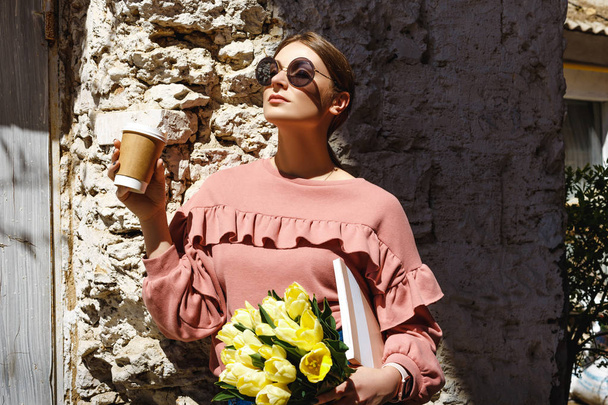 A girl stands near the urban wall with a cup of coffee - Φωτογραφία, εικόνα