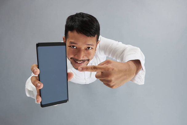 Щасливий азіатський чоловік вказує на смартфон
 - Фото, зображення