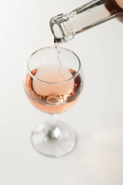 Transparent glass of wine. Pink wine. Festive mood. Alcohol for a group of friends. Delicious drink. Light background. Noble drink. Lavender and rose wine. Wine from lavender - Photo, Image
