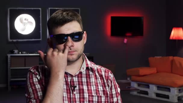 Aranyos fiatal szakállas férfi napszemüveg néz kamera és csákány az orrát - Felvétel, videó