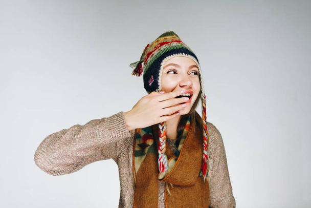 Funny girl in winter clothes with patterns makes a face and touches her nose - Photo, image