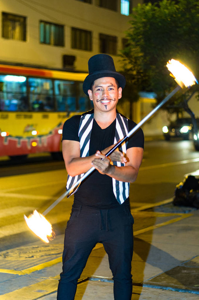 Een straat kunstenaar die een show maakt in Lima-Peru, jongleren met een stok met vuur bij stoplichten stopt - Foto, afbeelding