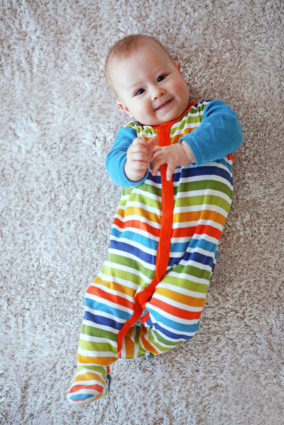 6 months baby lying down on a soft cozy carpet and looking at camera - Foto, Imagen