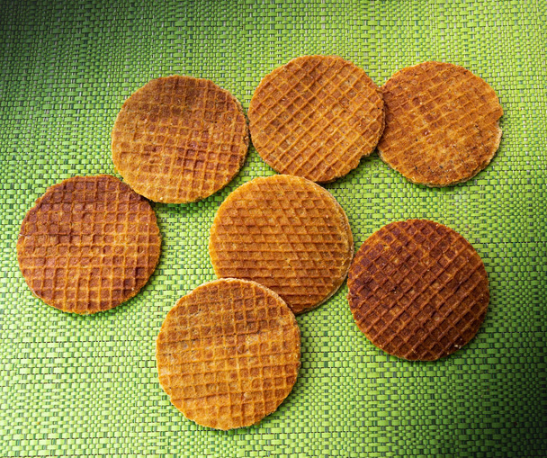 Stroopwafels irrigated spontaneously on a green tablecloth - Photo, Image