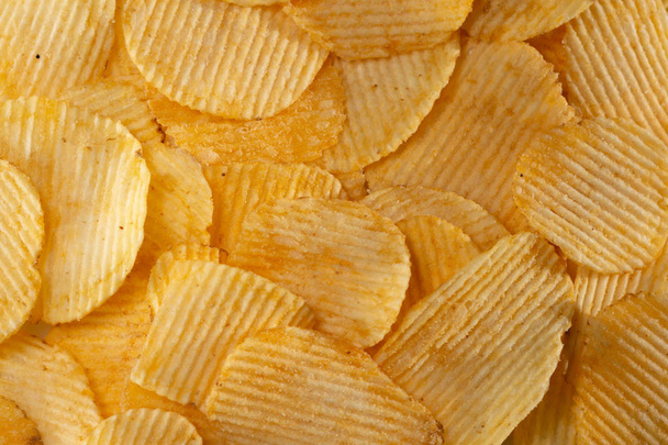 Gros plan beaucoup de savoureux fond de chips jaunes ondulées
 - Photo, image