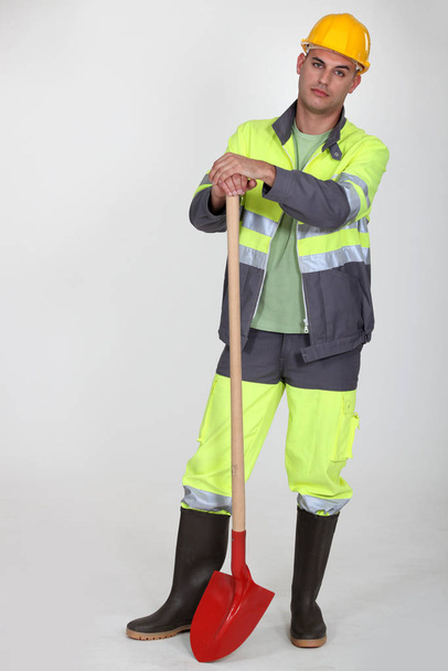 worker with shovel on grey background - Фото, изображение