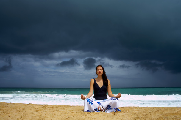 Vue de belle jeune femme pratiquant le yoga sur la plage orageuse
 - Photo, image