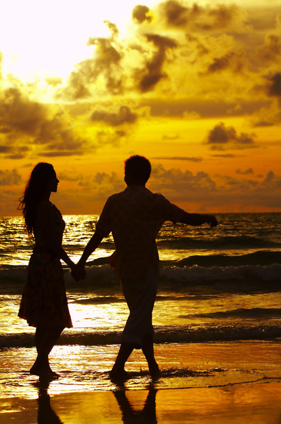 View of young couple walking along the shore during sunset - Photo, Image