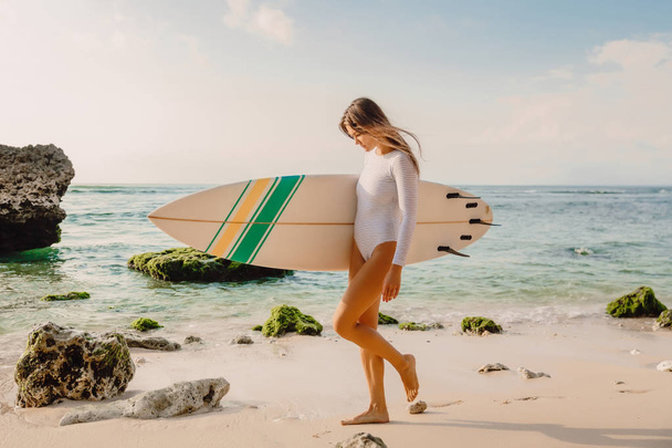 Aantrekkelijk surfer Girl met surfplank op strand. - Foto, afbeelding