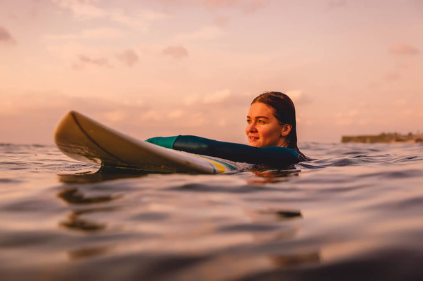 SurfGirl tökéletes test egy szörfdeszka úszó óceán. Szörfözés naplementekor - Fotó, kép