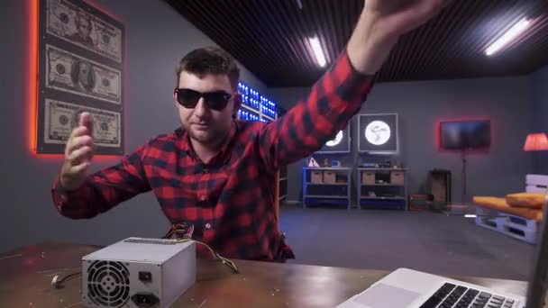 Bearded guy claps to camera having box of power supply with cooler put on desk. - Footage, Video
