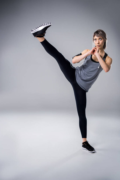 woman in sportive clothing training on grey - Valokuva, kuva