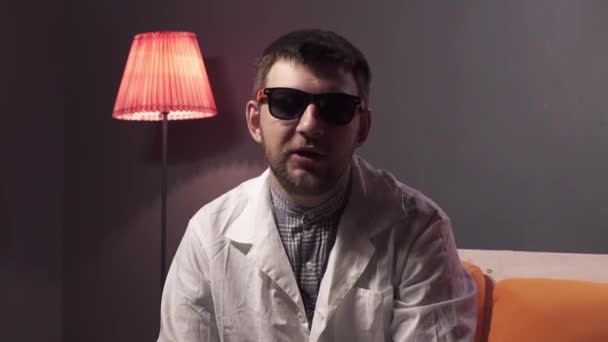 Kaukázusi Férfi szakáll visel napszemüveg és fehér labor kabát magyarázza cucc. - Felvétel, videó
