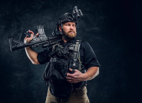 Un brave soldat des forces spéciales portant des uniformes de combat avec des dispositifs modernes posant avec un fusil d'assaut
. - Photo, image