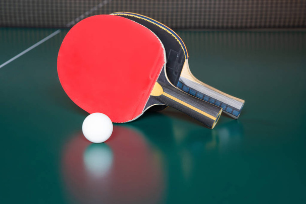 Dos raquetas de ping-pong y una pelota sobre una mesa verde. red de ping-pong
 - Foto, imagen