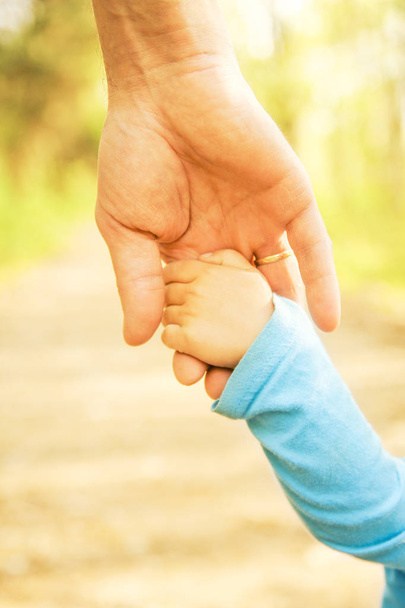 Mutlu bir geçmişi olan çocuğun elini tutan ebeveyn. - Fotoğraf, Görsel