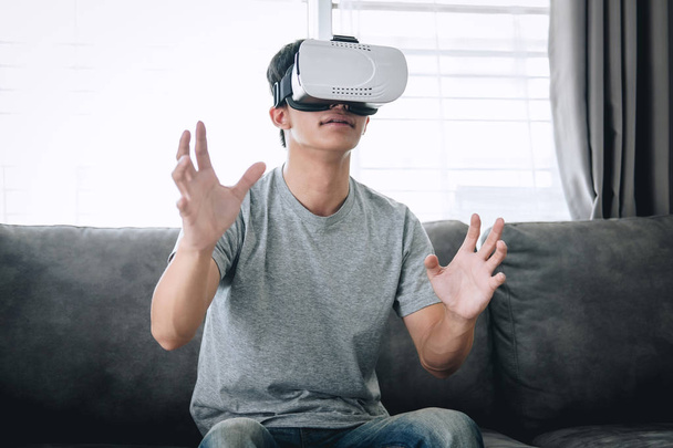 Young asian man having fun wearing playing virtual reality heads - Фото, изображение