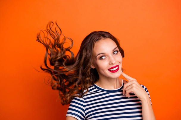 Close up photo beautiful she her lady red pomade hairdo curls flight overjoyed peaceful look empty space wondered wear casual striped white blue t-shirt clothes isolated orange bright background - 写真・画像