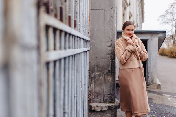 ahşap evler ve taş duvarlar yakınında şehir gezen bir kürk ceket genç şık sevimli kız - Fotoğraf, Görsel