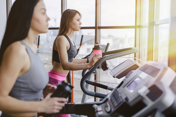 Girls in the gym are trained on treadmills and drink water, smiling - 写真・画像