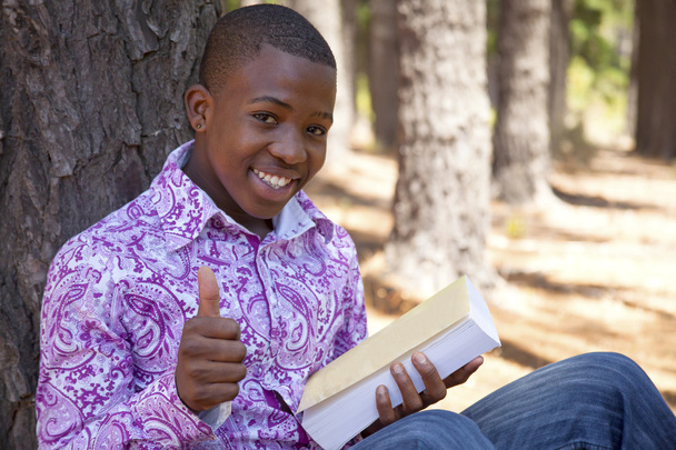 Ragazzo africano adolescente che legge un libro all'aperto
 - Foto, immagini