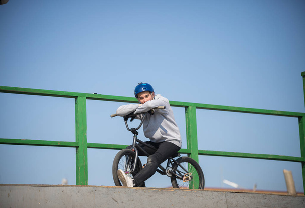A man in a helmet on a bicycle on the top of the half pipes - Photo, Image