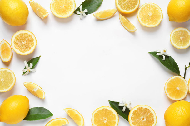Frame made of lemons, leaves and flowers on white background, top view with space for text. Citrus fruits - Valokuva, kuva