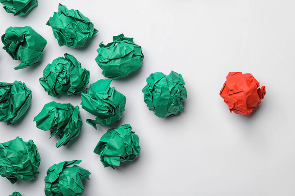 Green balls of crumpled paper following red one on white background, top view. Leadership concept - Фото, изображение