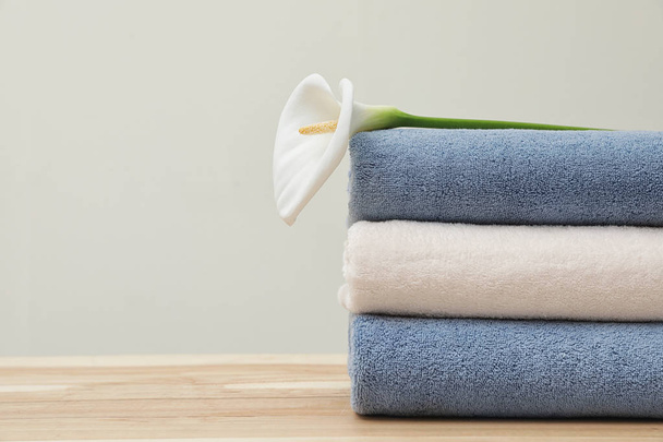 Stack of fresh towels with flower on table. Space for text - Foto, immagini