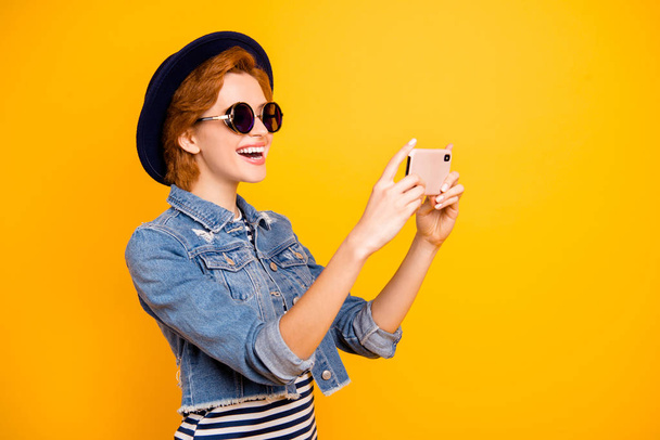 Close up side profile photo foxy she her lady modern telephone make take selfies speak tell skype wear specs vintage hat casual striped t-shirt jacket jeans denim isolated yellow bright background - Foto, immagini