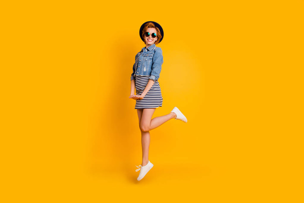 Full length side profile body size photo foxy she her chic lady jumping high sunny day fine weather weekend wear specs vintage hat casual striped dress jeans denim isolated yellow bright background - Φωτογραφία, εικόνα