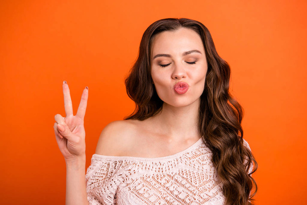 Close-up portrait of nice sweet tender attractive lovely winsome pretty cheerful cheery wavy-haired lady showing v-sign closed eyes isolated over bright vivid shine orange background - Foto, Imagem