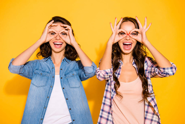 Portrait funny funky carefree careless playful beautiful hipsters make specs finger open mouth fool laugh laughter summer joke crazy free time yellow background isolated checked jeans long hair shirts - 写真・画像